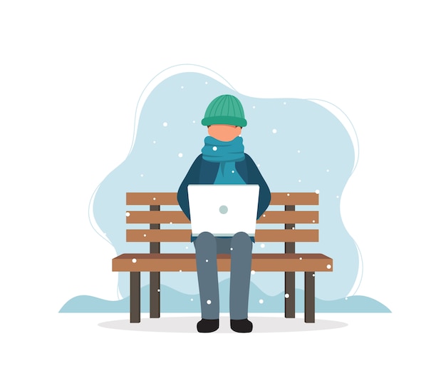 Man with laptop sitting on bench in winter.