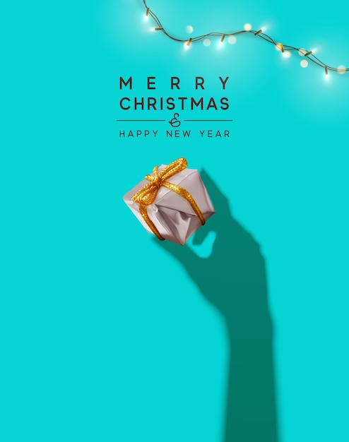 メリークリスマス、そしてハッピーニューイヤー。背景にリアルなギフトボックス、明るいクリスマスライトのガーランド。手からのシルエットの影はクリスマス プレゼントを保持します。クリエイティブな取得カード、ホリデー バナー