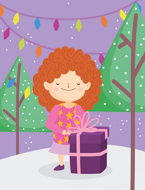 La bambina di buon natale con le luci brutte degli alberi del regalo del maglione nevica all'aperto