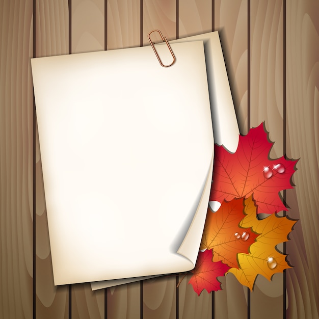 Paper sheet with autumn leaves on wooden table