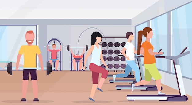 La gente che fa le esercitazioni uomini donne che lavorano insieme allenandosi in palestra che risolve orizzontale moderno interno dello studio del club di salute di concetto di stile di vita sano