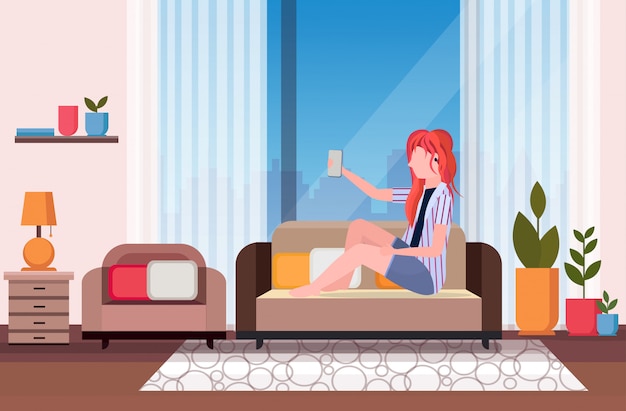 Roodharige vrouw zittend op bank meisje selfie foto nemen op smartphone camera moderne woonkamer interieur vrouwelijke stripfiguur volledige lengte horizontaal