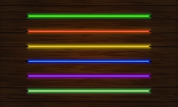 Набор неоновых кистей. набор красочных световых объектов на фоне темного дерева.