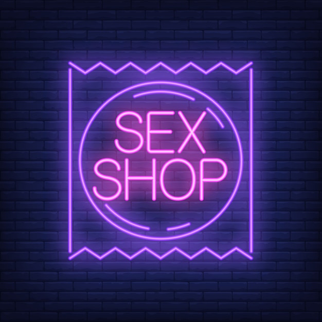 Insegna al neon del sexshop. pacchetto del preservativo sul muro di mattoni.