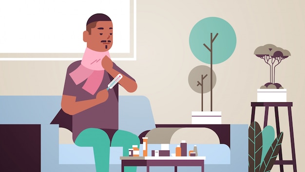 Sick man measuring temperature with thermometer unhealthy african american guy in scarf suffering from cold flu virus illness concept modern living room interior flat portrait horizontal