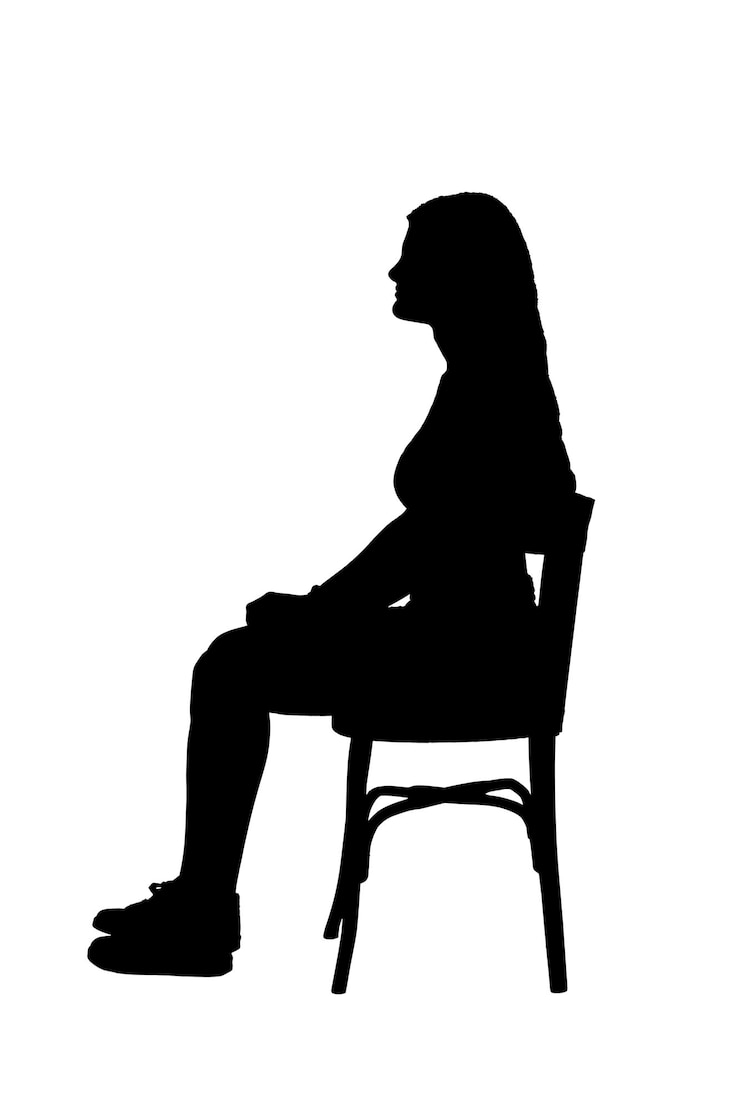 side view of a young girl sitting on chair on white background