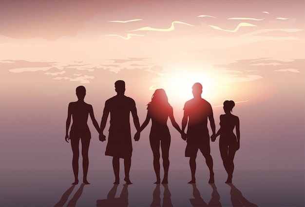 Silhouet mensen groep staan hand in hand man en vrouw volledige lengte op zonsondergang achtergrond