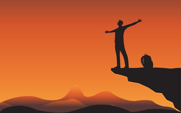 Silhouette of man standing relax on mountain cliff