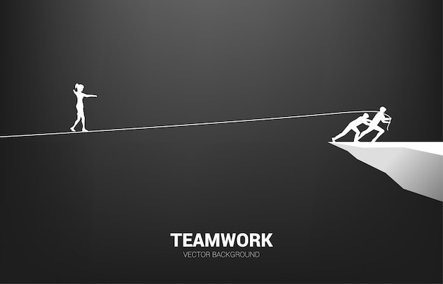 チームによって引っ張られたロープの散歩道を歩いて実業家のシルエット。チームワークとチームのサポートの概念。
