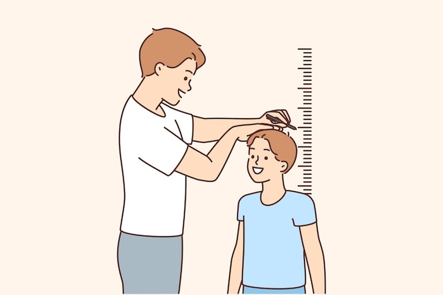 Smiling father measure son height near wall