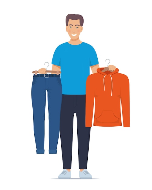 Smiling young man holding hangers with trousers and sweatshirt Choosing clothes concept