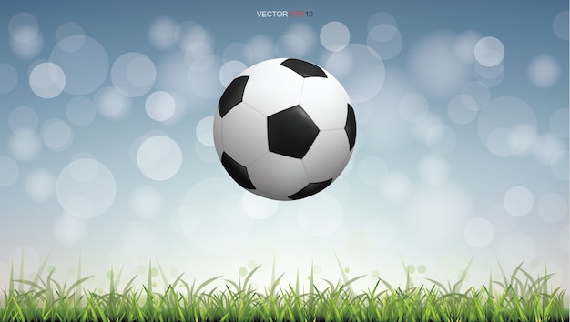 Soccer football ball on green grass field with light blurred bokeh background