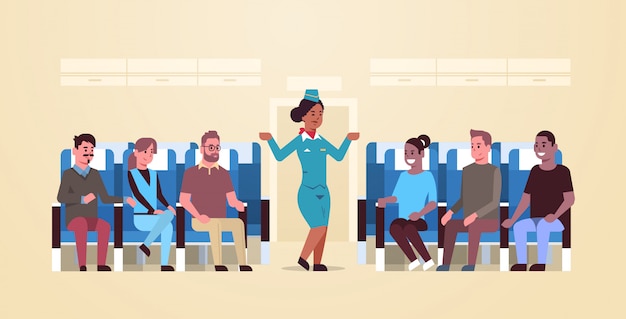 Stewardess explaining instructions for mix race passengers african american flight attendant in uniform showing emergency exits safety demonstration concept airplane board interior horizontal