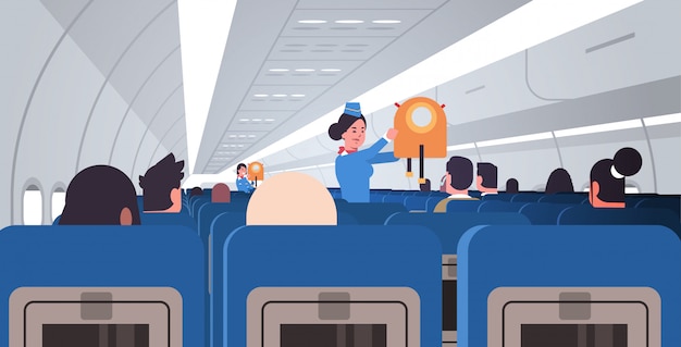 Стюардесса стюардесса объясняет пассажирам, как использовать спасательный жилет в аварийной ситуации безопасность демонстрация концепция современный самолет доска интерьер горизонтальный плоский