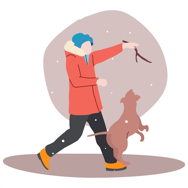 真冬にティーンエイジャーが犬と遊んでいます。