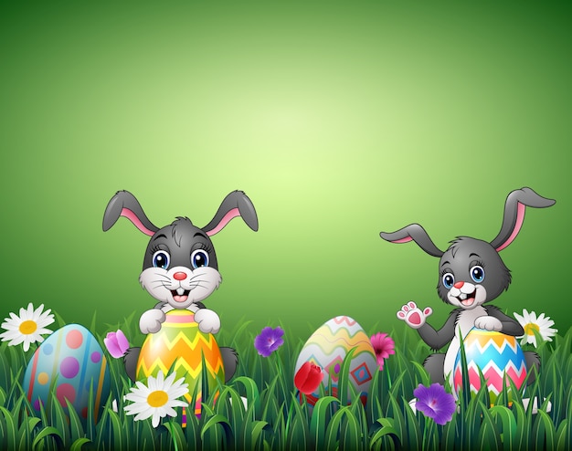 Two happy rabbit cartoons with easter eggs in a field