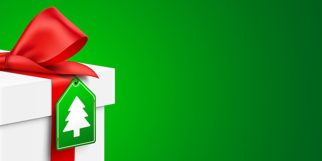 White gift box with Christmas Tree hanging tag on a green background realistic vector banner