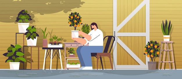 Woman gardener taking care of potted orange plant at backyard greenhouse or home garden horizontal