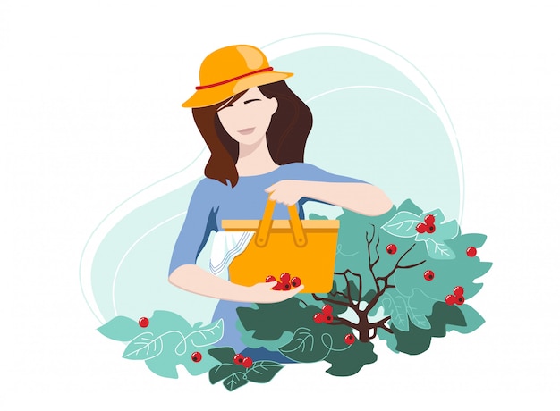 Woman in a hat picking red berries in a bag on her backyard