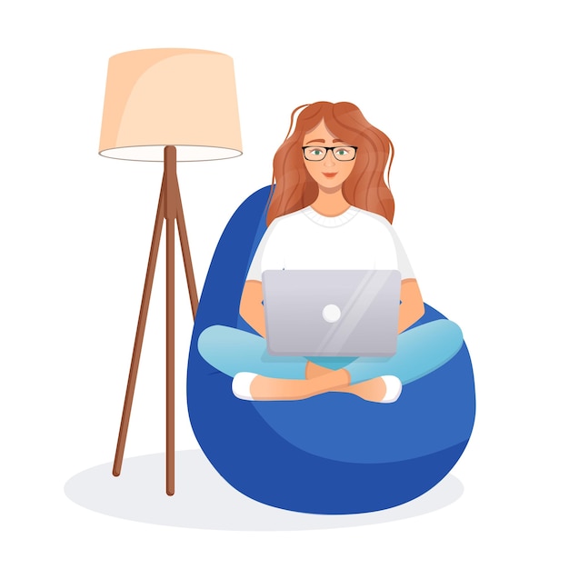 Woman sits on the bean bag chair and works at the computer remote work office at home programming