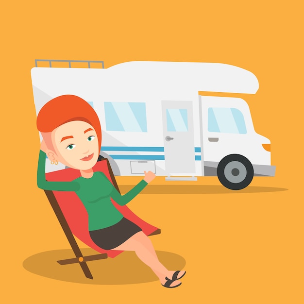 Woman sitting in chair in front of camper van.