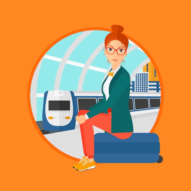 Женщина сидит на чемодане на вокзале.