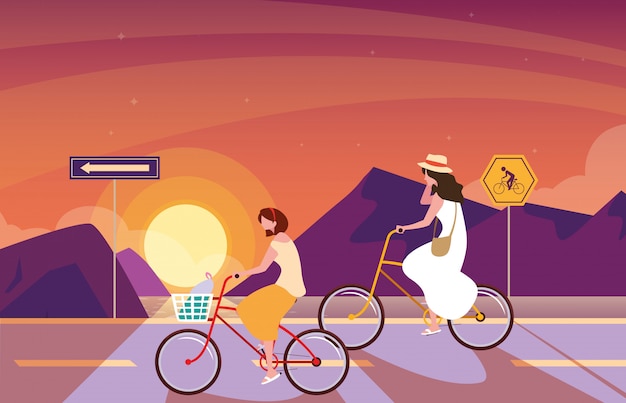 Donne in sella a bici nel paesaggio di alba con segnaletica per ciclista