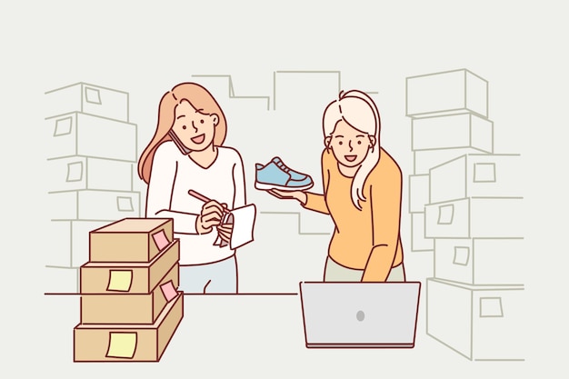 Women small business owners making fulfillment startup stands among cardboard boxes and uses laptop Girls make career in fulfillment of company and sale of goods through internet marketplaces