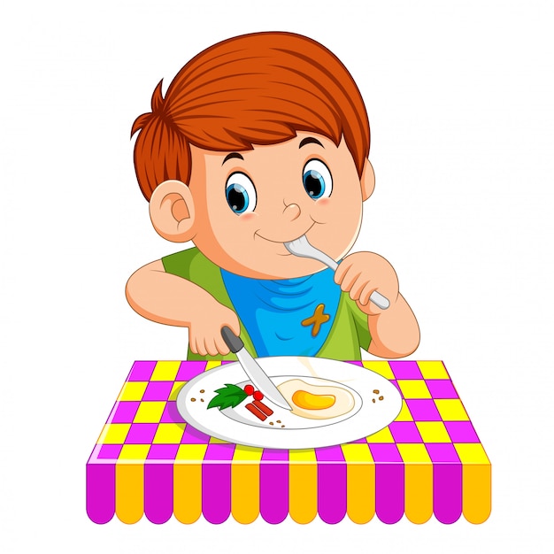 A young boy sitting while enjoy having breakfast