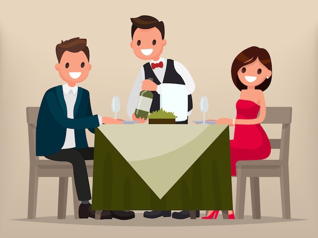 young couple having dinner in a restaurant. man and woman sitting at the table, the waiter shows the wine.