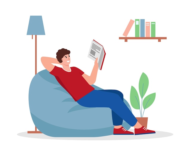 젊은 남자가 안락의자에 앉아 책을 읽고 있다. 퇴근 후 빈백 위에서 휴식을 취하는 남성