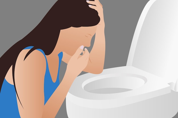 A young woman vomits into the toilet during early pregnancy or after a party and drinking