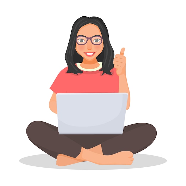 Young woman with glasses using laptop computer while sitting on a floor showing thumb up