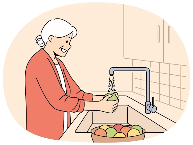 elderly woman washes fruits in sink standing in kitchen and observing rules of hygiene