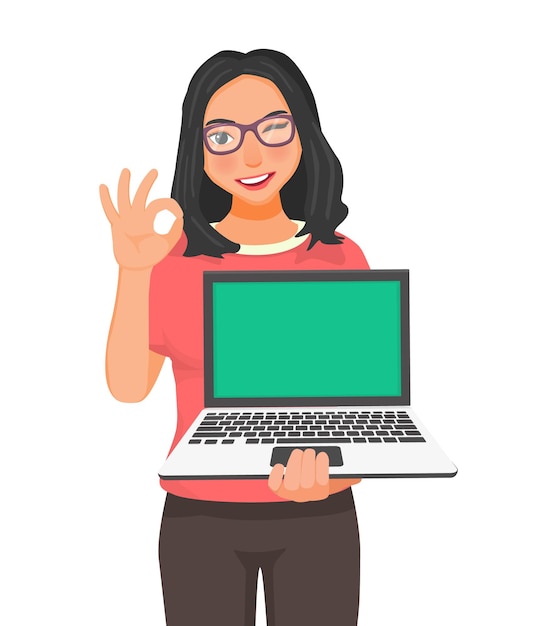 Young woman with glasses holding laptop with blank screen for copy space showing okay gesture