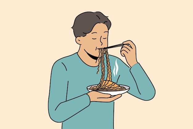 Azjata je ramen z chińskimi pałeczkami, ciesząc się smakiem tradycyjnego narodowego posiłku z restauracji z kuchnią koreańską Facet stoi i lubi jeść ramen lub makaron, aby uzyskać wystarczającą ilość podczas przerwy w pracy