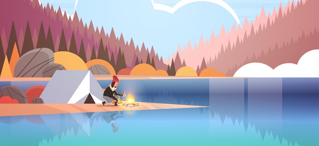 Kobieta Turysta Płonący Ogień W Pobliżu Namiotu Obóz Dziewczyna Trzyma Drewno Na Ognisko Turystyka Camping Koncepcja Jesień Krajobraz Natura Rzeka Las Góry
