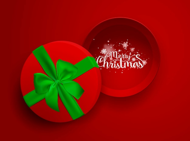 Świąteczny napis w otwartym czerwonym pudełku z zieloną wstążką i kokardą na czerwonym tle