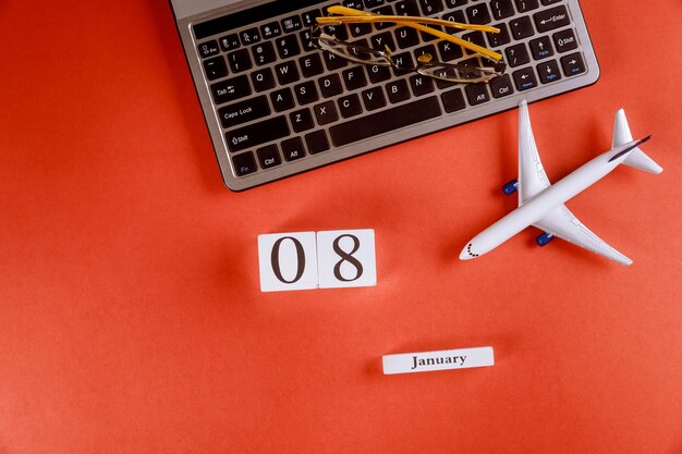 Zdjęcie 08 stycznia kalendarz z akcesoriami na biznesowym biurku biurka na klawiaturze komputera, samolot, okulary czerwone tło
