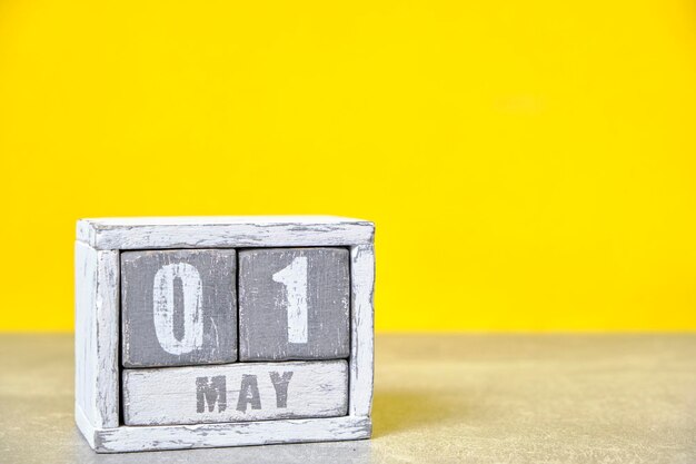 1 maja Drewniany kalendarz na biurko żółte tłoMiesiąc wiosny przedstawiony na kostkachMiejsce na Twoje pomysłyŚwięto pracy