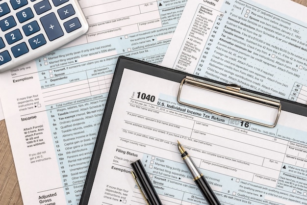 1040 formularz podatkowy na drewnianym stole z długopisem i kalkulatorem