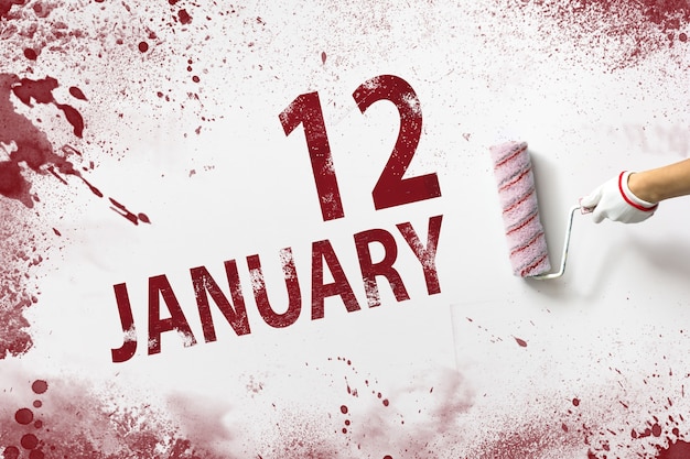 Zdjęcie 12 stycznia dzień 12 miesiąca data w kalendarzu ręka trzyma wałek z czerwoną farbą i pisze