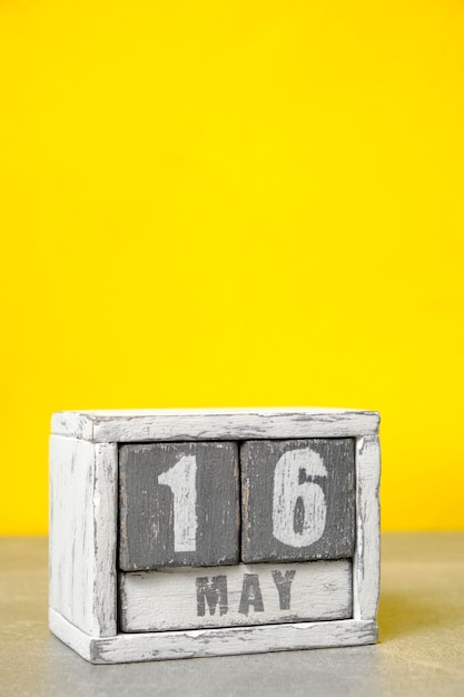 Zdjęcie 16 maja kalendarz wykonany z drewnianych kostek żółtym tle z pustym miejscem na tekst
