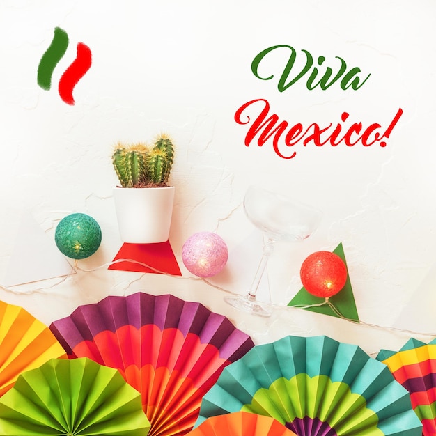 Zdjęcie 16 września meksyk szczęśliwy dzień niepodległości karta powitalna viva meksyk tradycyjny meksykański zwrot świąteczny z papierowymi wentylatorami lekki wieniec kaktus i szklankę na białym tle płaskie położenie