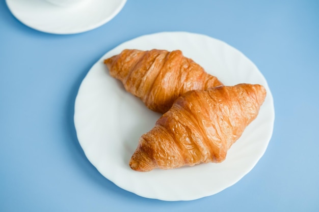 2 duże rogaliki na białym talerzu na niebieskim tle Poranne śniadanie we Francji Fresh Baking własnymi rękami