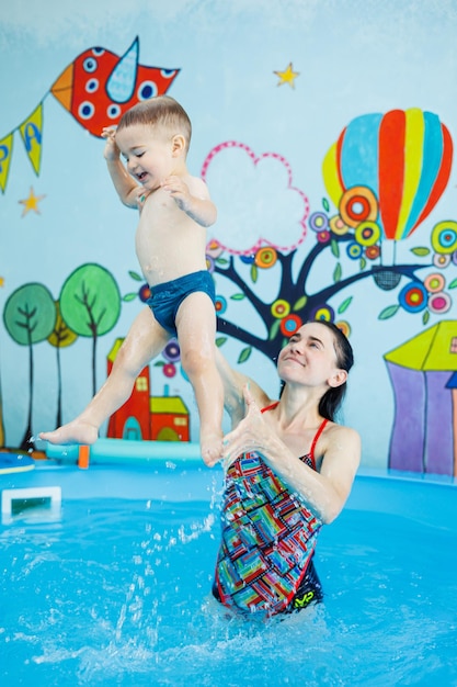 2-letni chłopiec uczy się pływać w basenie z trenerem Nauka pływania dla dzieci Szkoła pływania dla dzieci Edukacyjne kursy pływania dla dzieci