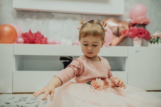 2-letnia dziewczynka w różowej sukience z pierwszym tortem urodzinowym wszystkiego najlepszego carda śliczna mała dziewczynka świętuje swoje pierwsze urodziny otoczona prezentami