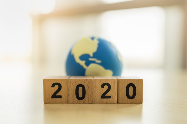 Zdjęcie 2020 nowy rok, koncepcja globalna i biznesowa. zamyka up sterta drewniany liczba blok i mini świat zabawkarska piłka z kopii przestrzenią