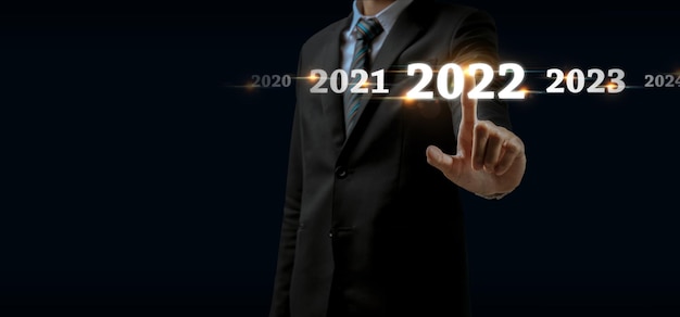 2022. ręka biznesmena dotykająca i wskazująca na rok 2022 z wirtualnym ekranem na ciemnym tle, cel celu, zmiana z 2021 na 2022, strategia, inwestycja, planowanie biznesowe, koncepcja szczęśliwego nowego roku