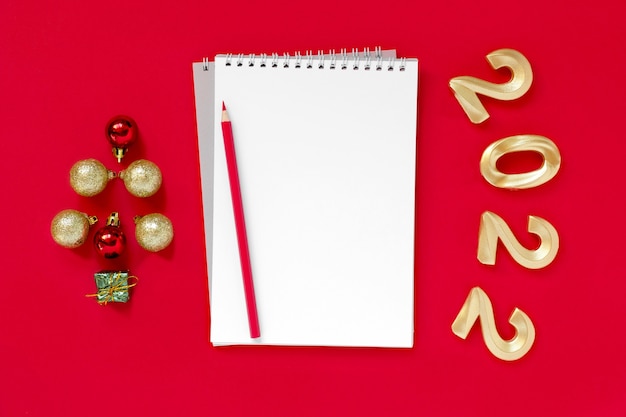 2022 ułóż na czerwonym tle Notatnik z białym ołówkiem do pisania Złote liczby 2022